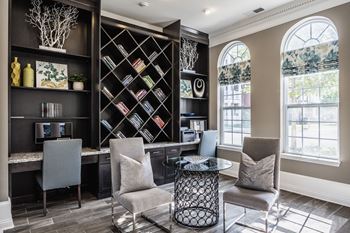 A living room with chairs and a table and a book shelf